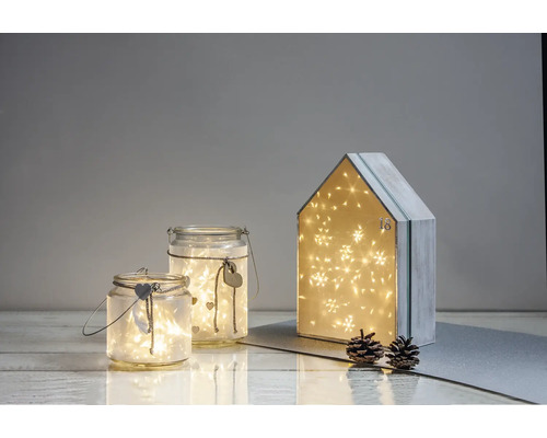 Scène décorative avec photophores en verre et une maison de calendrier de l''Avent, éclairée avec des lumières