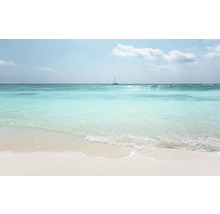 Une plage de sable clair avec une mer turquoise et un voilier à l'horizon