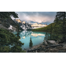 Lac de montagne entouré de sommets enneigés et de conifères