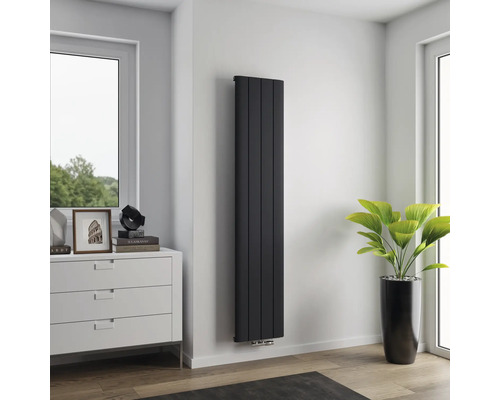 Hoher, schmaler Heizkörper an einer Wand in einem Raum.