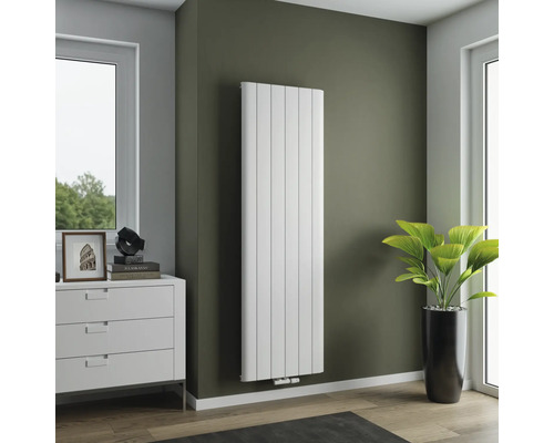 Radiateur vertical dans un salon avec commode et plante d'intérieur.