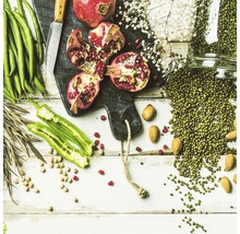Arrangement mit Granatäpfeln, grünen Bohnen, Mandeln und Mungobohnen auf einem Schneidebrett
