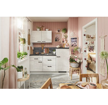 Cuisine lumineuse avec armoires blanches, plan de travail aspect pierre et décoration murale rose pour une ambiance conviviale.