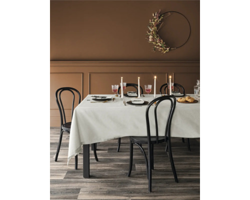 Esstisch mit Gedeck, Stühlen und floralem Wandkranz in einem Esszimmer.