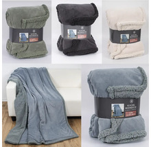 Plusieurs couvertures douillettes de différentes couleurs, partiellement emballées, partiellement drapées sur un canapé.