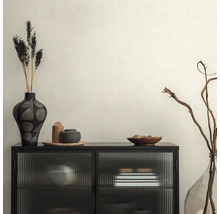 Intérieur décoratif avec armoire noire, vases et fleurs séchées sur papier peint beige.