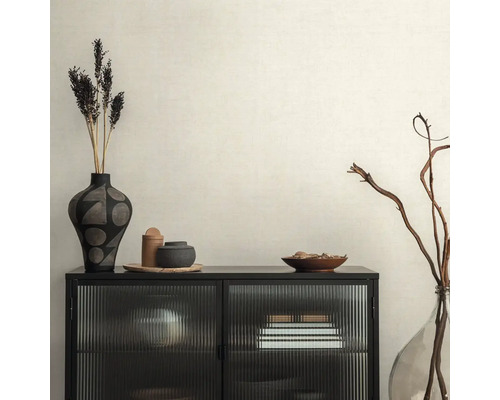 Intérieur décoratif avec armoire noire, vases et fleurs séchées sur papier peint beige.