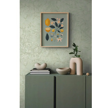 Dekorative Szene mit einer Kommode, darauf eine Dekoschale, Bücher und eine Vase, an der Wand ein Bild mit Zitronenmotiven