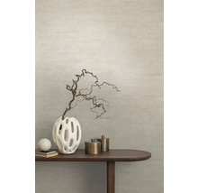 Dekorative Vase mit Zweig auf einem Holztisch vor einer strukturierten Wand