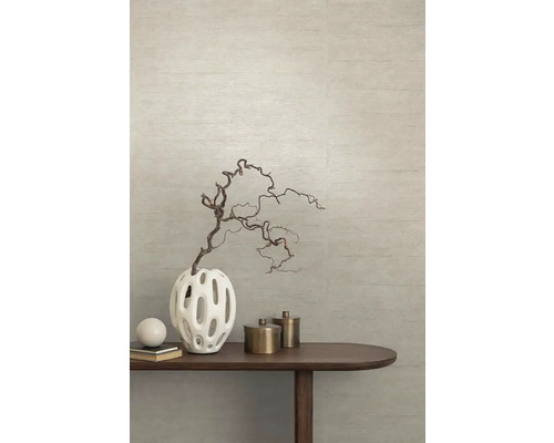 Dekorative Vase mit Zweig auf einem Holztisch vor einer strukturierten Wand