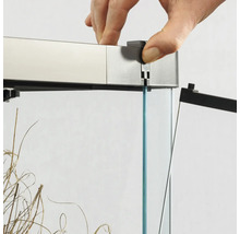 Detailansicht eines Aquariums mit Glasabdeckung und einer Hand, die die Abdeckung anbringt