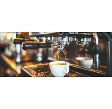 Kaffee fliesst aus enger Espressomaschin an eng Taass.