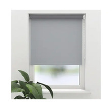 Rollo zur Fensterabdunklung mit Kettenzug an einem Fenster mit einer Zimmerpflanze im Vordergrund