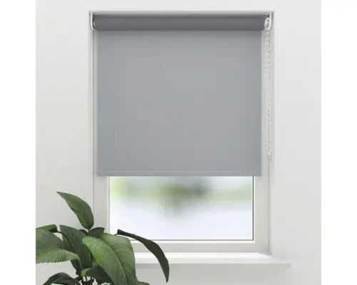 Rollo zur Fensterabdunklung mit Kettenzug an einem Fenster mit einer Zimmerpflanze im Vordergrund