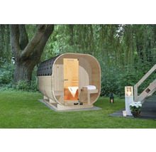 Sauna en tonneau de bois dans le jardin avec arbre et éclairage de jardin