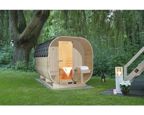 Sauna en tonneau de bois dans le jardin avec arbre et éclairage de jardin