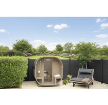 Vue du jardin avec sauna tonneau, chaise longue et clôture devant la pelouse