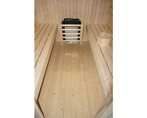 Aménagement intérieur d'un sauna avec bancs, poêle de sauna avec pierres et seau en bois