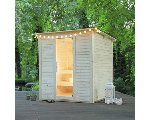 Sauna en bois à l'extérieur avec guirlande lumineuse et porte ouverte