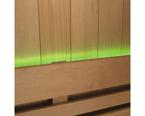 Gros plan d'un banc de sauna devant un lambris en bois avec éclairage vert