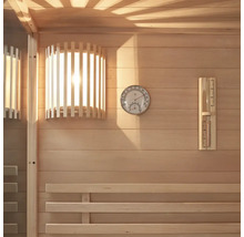 Vue intérieure d'un sauna avec lambris en bois, lampe, thermomètre et hygromètre.
