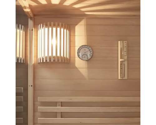 Vue intérieure d'un sauna avec lambris en bois, lampe, thermomètre et hygromètre.
