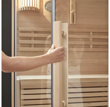 Main ouvrant la porte du sauna avec façade en verre et cadre en bois