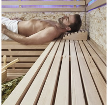 Mann entspannt in einer Sauna mit Holzbänken und Zubehör.