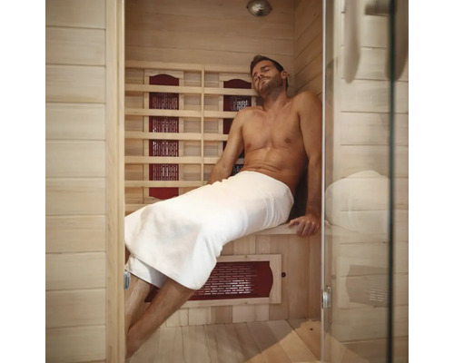 Homme se détendant dans un sauna infrarouge avec des murs en bois et une façade en verre