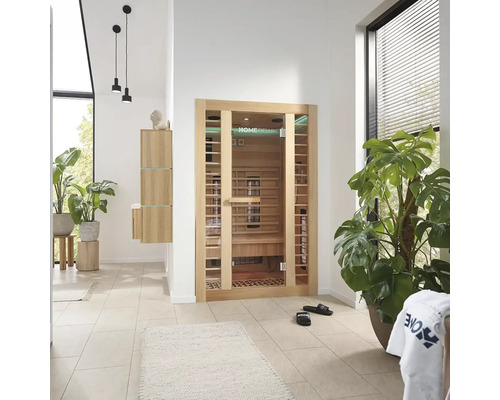 Pièce lumineuse avec sauna Home Deluxe, plantes et meubles de salle de bains.