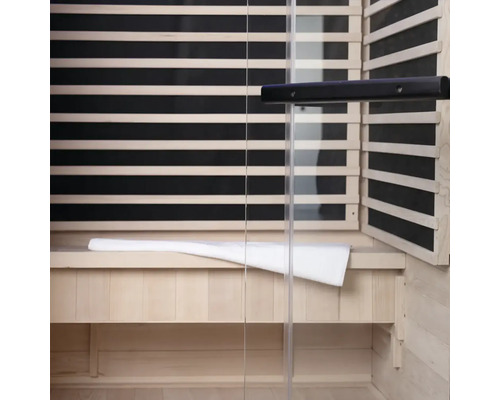 Vue intérieure d'un sauna avec lambris en bois, façade en verre et banc avec serviette