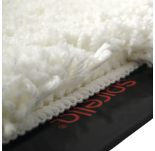 Vue détaillée d'un tapis de bain blanc à poils longs avec le logo Spirella.