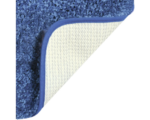 Detailansicht eines blauen Teppichs mit gewendeter Ecke, die die Rückseite zeigt