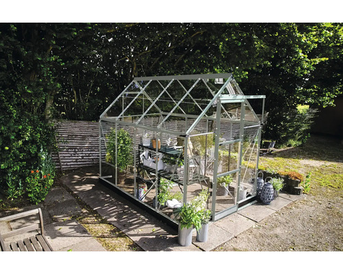 Gewächshaus im Garten mit Pflanzen und Gartenzubehör