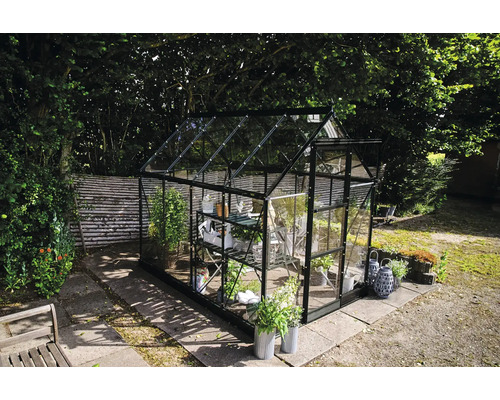 Gewächshaus mit Glaswänden und Regalen im Garten