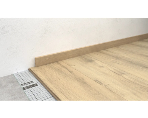 Pose d'un sol stratifié avec plinthe et sous-couche isolante.