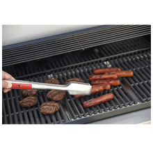 Barbecue avec hamburgers, saucisses et pince de barbecue