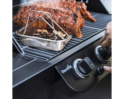 Barbecue avec côtes levées, boîte à fumer et copeaux de bois ainsi qu'une main sur un bouton