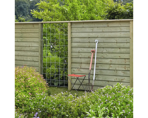 Vue de jardin avec clôture en bois, treillis, outils de jardin et tabouret de jardin