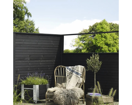 Dekorative Gartenszene mit Holzzaun, Pflanzkübel, Rattansessel und Pflanzen