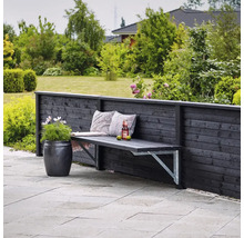 Scène de jardin avec banc en bois contre une clôture en bois, coussins décoratifs, boisson et pot de fleurs.