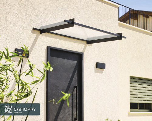 Marquise de porte moderne avec cadre en métal noir et panneau transparent au-dessus d'une porte d'entrée sombre.