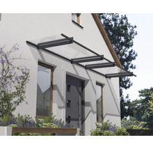 Marquise de porte moderne en verre avec cadre en métal foncé au-dessus d une porte d entrée sur une façade lumineuse.