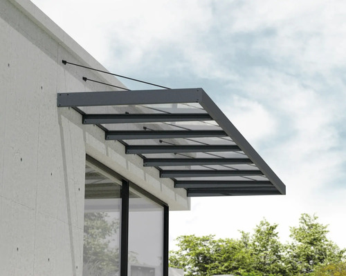 Marquise de porte moderne en verre avec cadre en aluminium anthracite et suspension par câbles sur une façade claire.