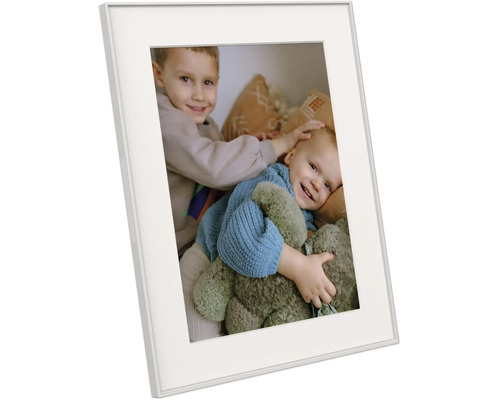 Cadre photo blanc avec passe-partout, présenté de biais, contenant une photo de deux enfants souriants avec un ours en peluche.