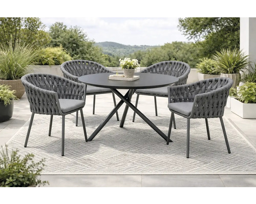Ensemble de meubles de jardin avec table ronde et quatre chaises sur un tapis à l'extérieur.