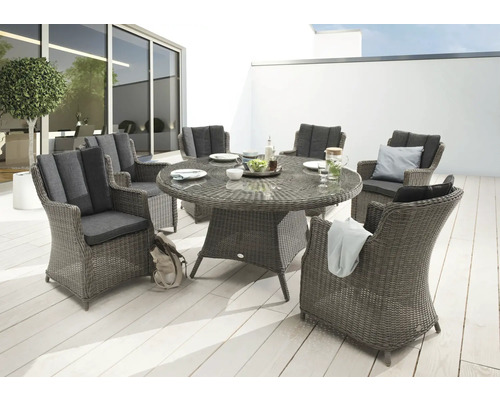 Scène de jardin avec une table à manger ronde en rotin et six fauteuils assortis avec coussins sur une terrasse.