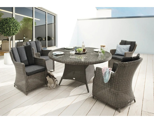 Scène de jardin avec table à manger ronde et quatre fauteuils en osier à l'extérieur