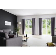 Wohnzimmer mit Sofa, Fenstern mit Vorhängen und Stehlampe