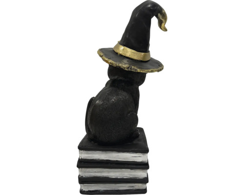 Chat noir décoratif avec chapeau de sorcière sur une pile de livres